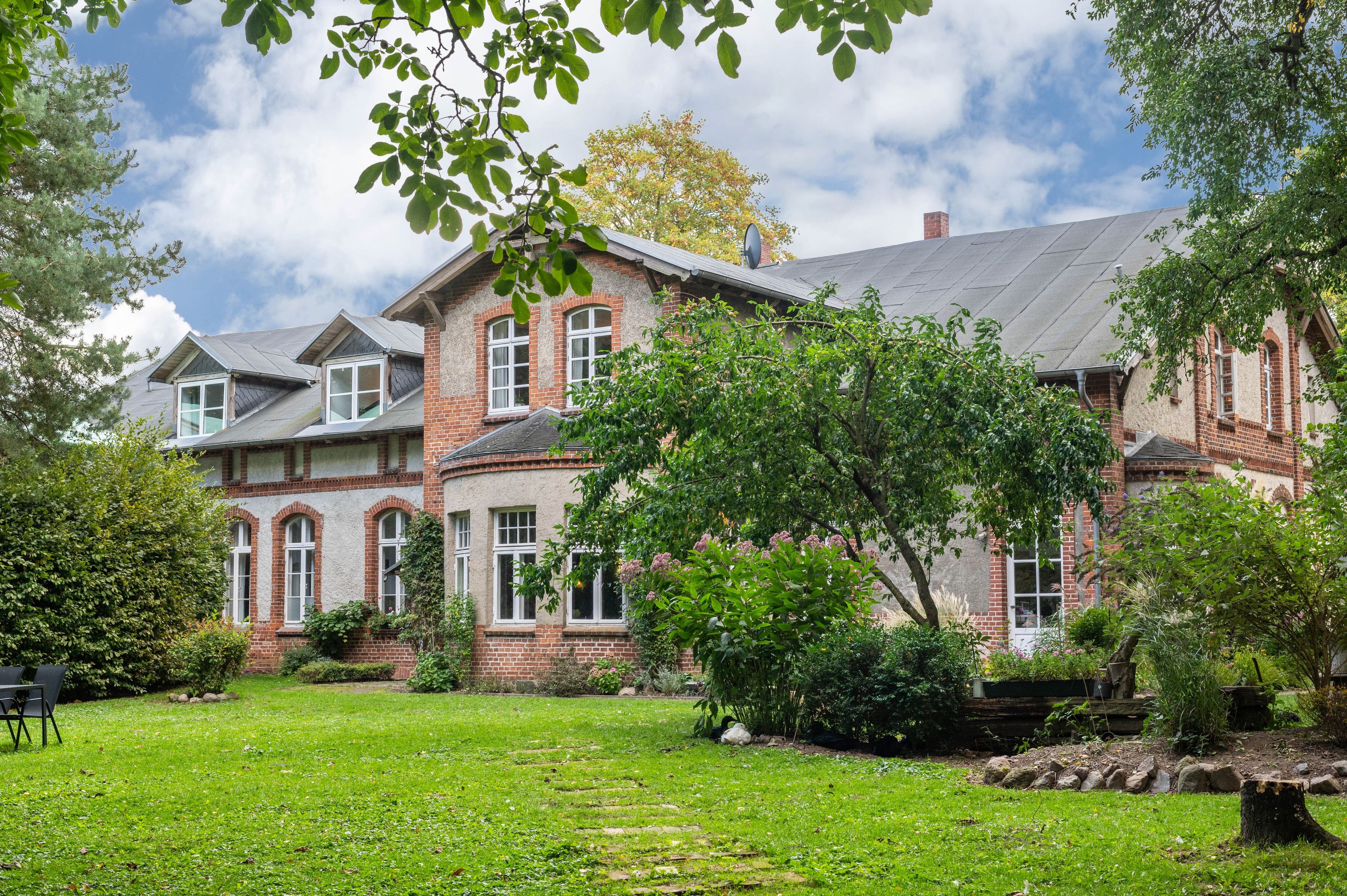 Un grand bâtiment en briques, doté de nombreuses fenêtres et d’un jardin bien entretenu à l’avant.