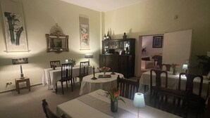 Comedor con mesa dispuesta para cuatro personas, rodeada de sillas, un aparador y un cuadro en la pared.