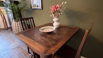 A dining table with chairs, a vase with flowers, a framed picture on the wall, and a plant.