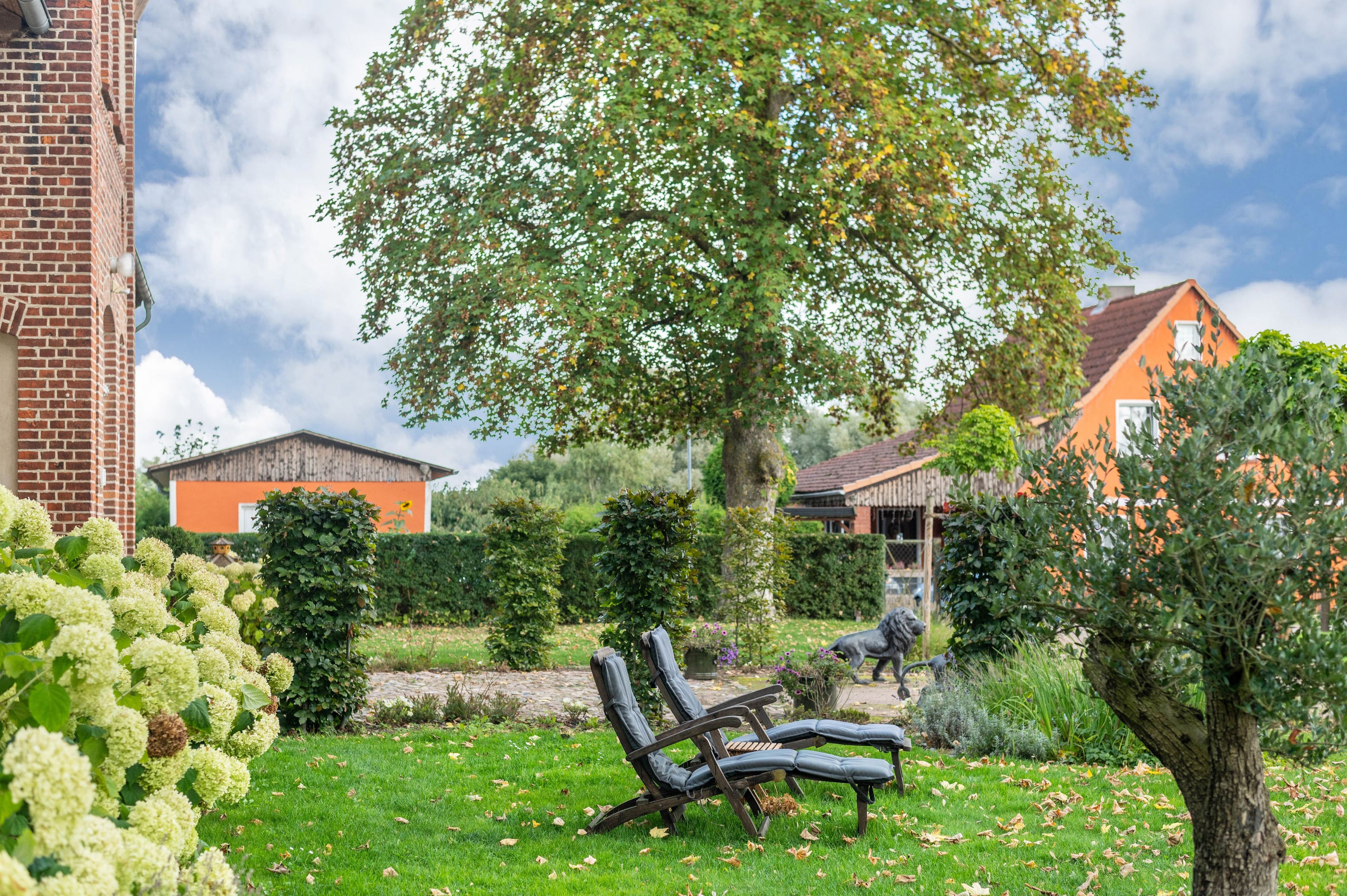 Ein Garten mit einer Bank, einem Baum und einem Backsteinhaus.