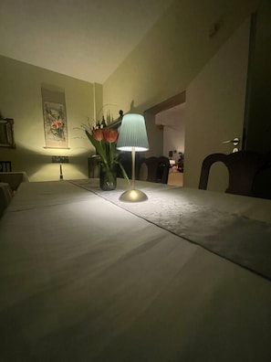 Ein Esstisch mit Blumen in einer Vase und einer Lampe.