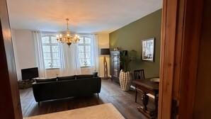 Un salón amplio con un sofá grande, una mesa de comedor y una araña.