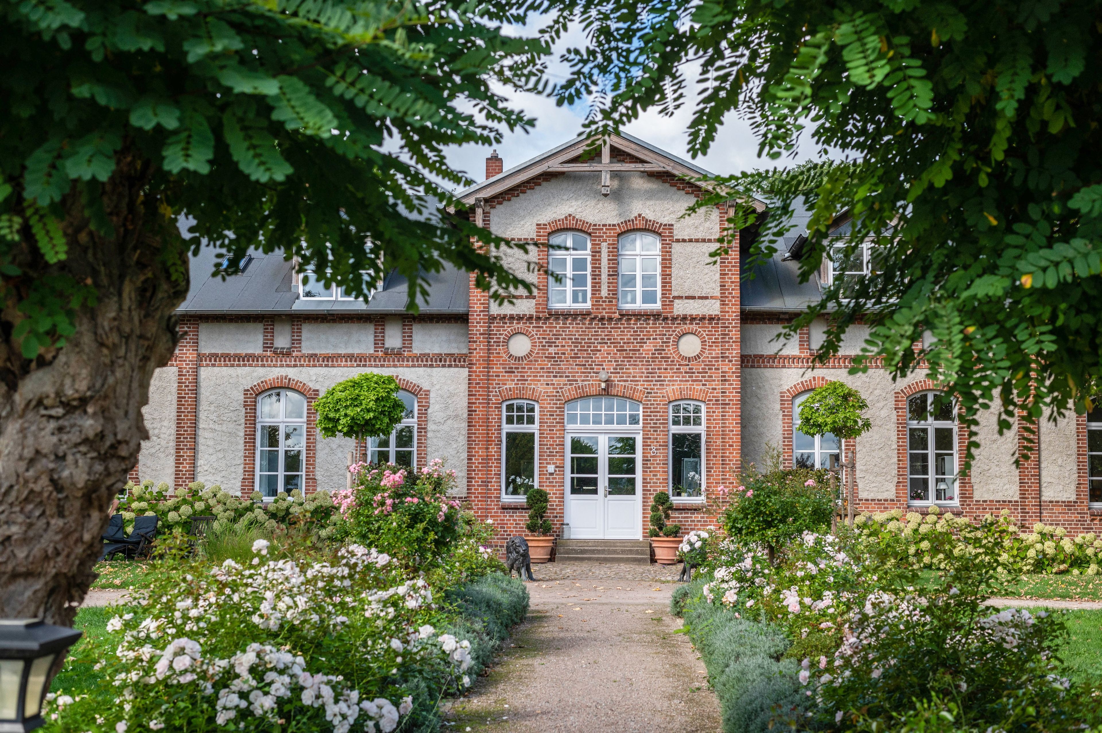 A traditional brick building with a symmetrical facade, large windows, and a central entrance.