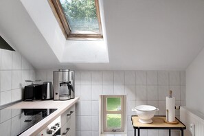 Una cocina moderna con tragaluz, cafetera, colador y radiador.