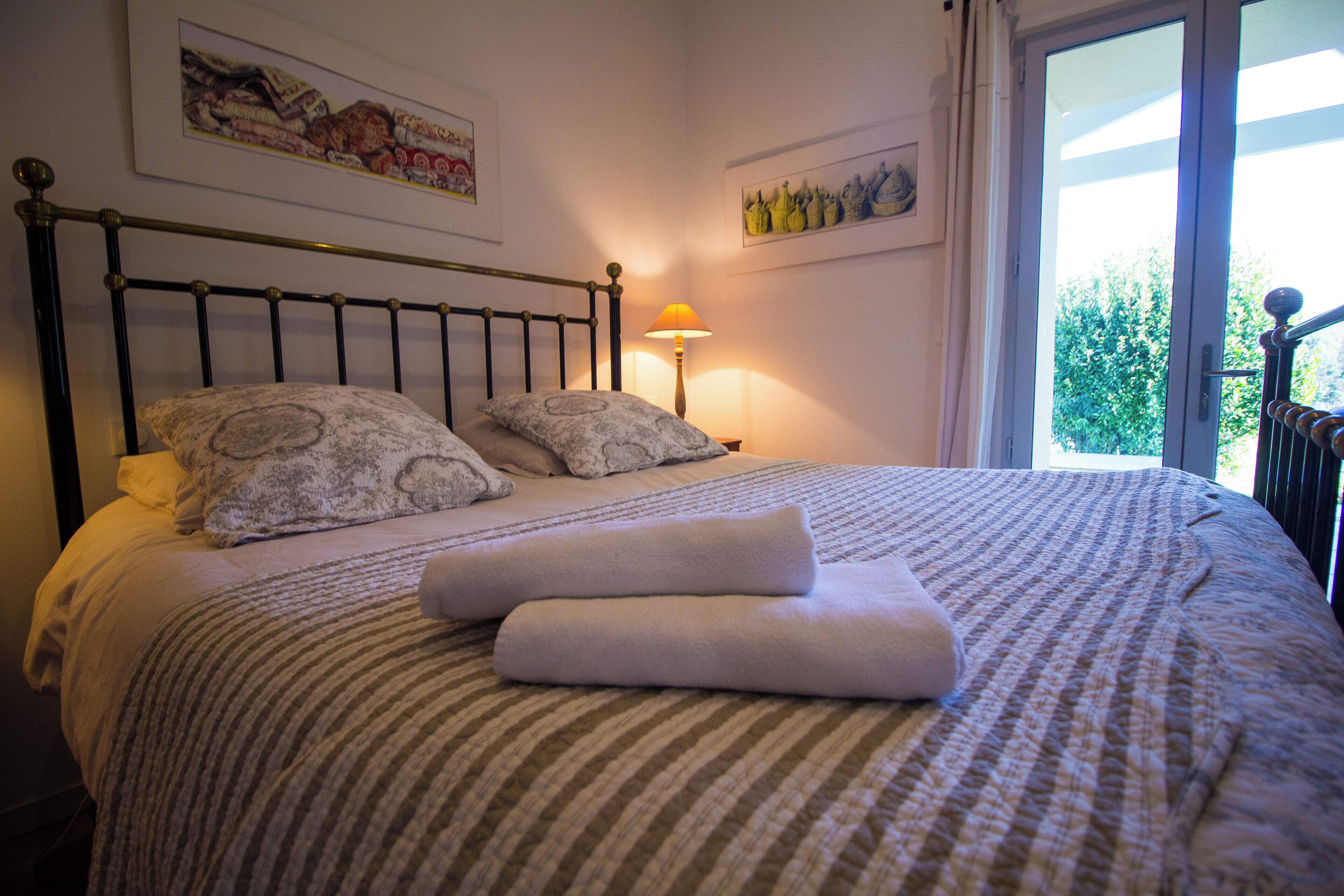 A neatly made bed with a striped bedspread, two pillows, and a folded towel.