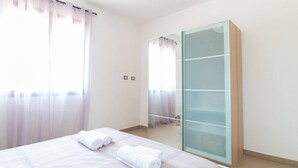 Ett hotellrum med en säng, en garderob med glasdörrar och utsikt genom fönstret.