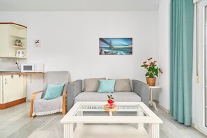 Un soggiorno con divano, poltrona, tavolino da caffè e un quadro raffigurante un ponte.