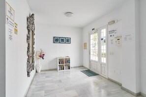 Un corridoio con una porta bianca, una libreria bianca e una parete bianca decorata con quadri.