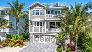 A two-story house with a balcony, a garage, and a well-maintained garden with various plants and a paved driveway. - Beach & Bay by Beach Boutique Rentals (Bradenton Beach)