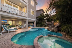 A two-story building with a pool area featuring lounge chairs, a barbecue, and a waterfall. - Beach & Bay by Beach Boutique Rentals (Bradenton Beach)