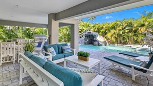 An outdoor patio with a pool, a waterfall feature, and lush tropical vegetation. - Beach & Bay by Beach Boutique Rentals (Bradenton Beach)