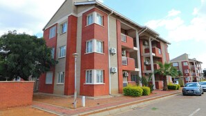 Un edificio residenziale a più piani con facciata in mattoni, diversi balconi e un vialetto lastricato.