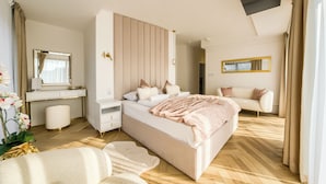 A bedroom with a bed, bedside tables, a dresser, a mirror, a sofa, and a potted plant. - Apartamenty Sun & Snow Greeneri Park (Świnoujście)