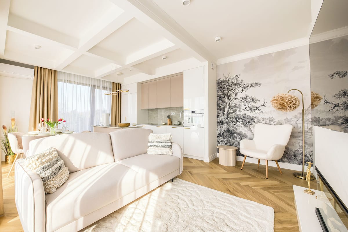 A modern living room with a sofa, a coffee table, and a dining area with a kitchen in the background.