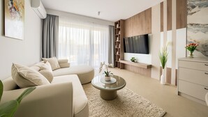A modern living room with a sofa, a coffee table, a TV, and a bookshelf. - Apartamenty Sun & Snow Greeneri Park (Świnoujście)