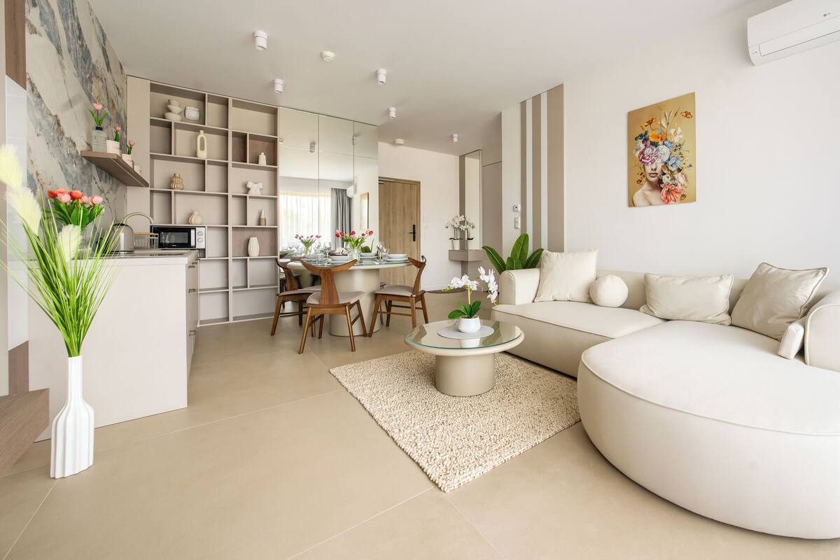 A modern living room with a sofa, coffee table, and dining area.