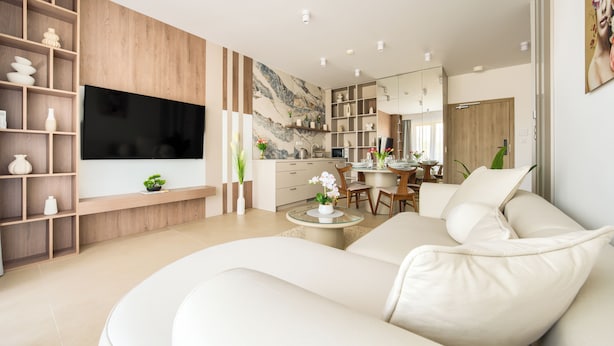 A modern living room with a large flat-screen TV, a sofa, and a dining area with a table and chairs. - Apartamenty Sun & Snow Greeneri Park (Świnoujście)