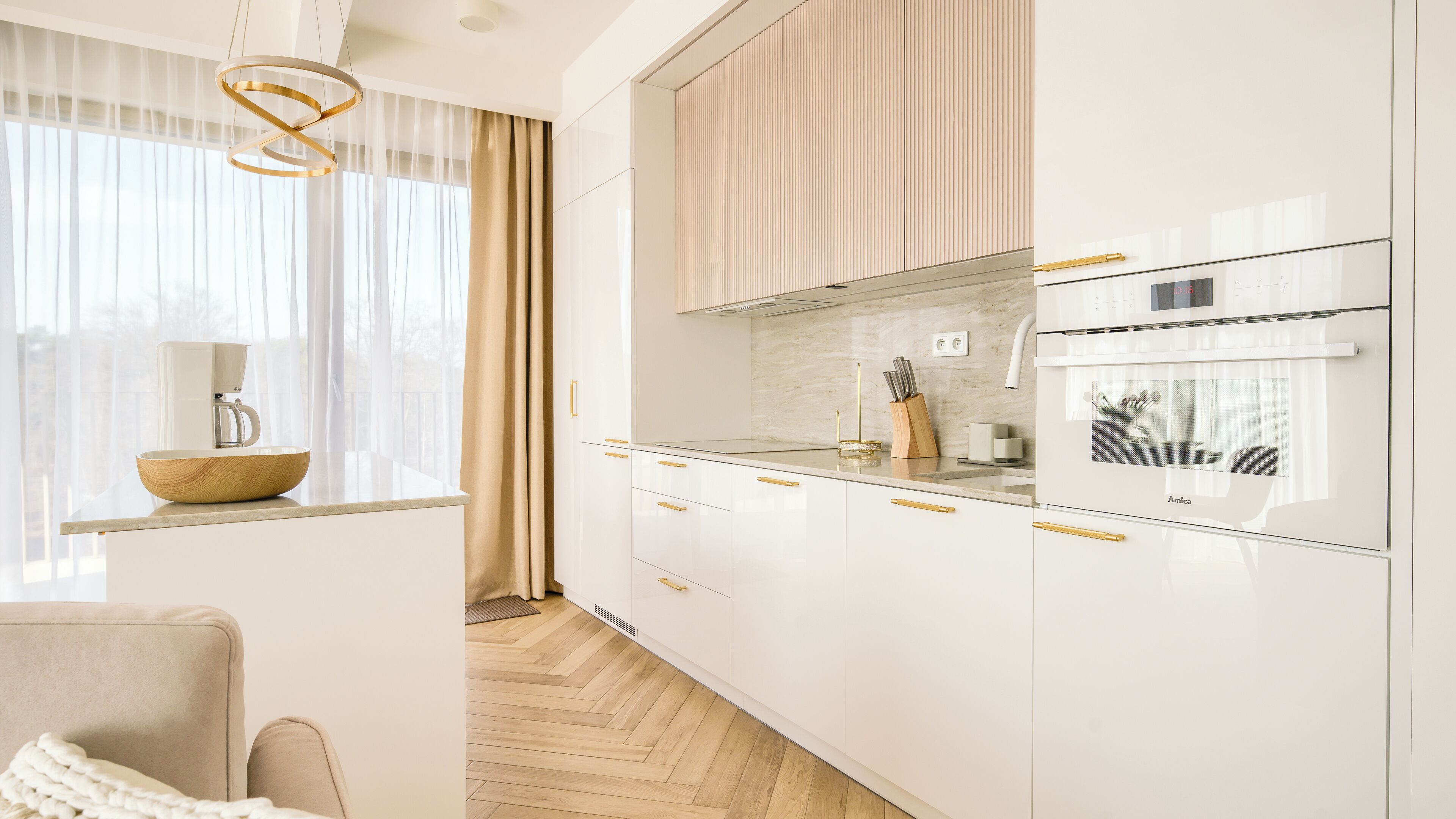 A modern kitchen with white cabinetry, a coffee maker, and a wooden bowl on the counter.