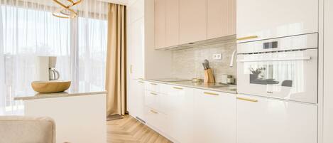 A modern kitchen with white cabinetry, a coffee maker, and a wooden bowl on the counter.