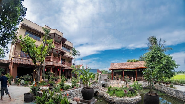 A courtyard with a pond, potted plants, and traditional architecture. - Y Van Cac Homestay (Tay Hoa Lu)