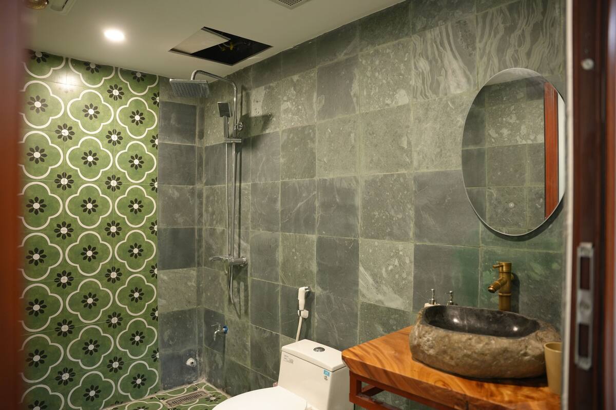 Un baño con ducha, inodoro, lavamanos y espejo.