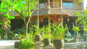 A multi-story building with a traditional architectural style, featuring balconies and a courtyard with potted plants and a stone wall. - Y Van Cac Homestay (Tay Hoa Lu)