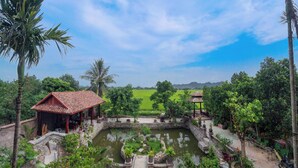 A courtyard with a pond, a gazebo, and a small building with a tiled roof. - Y Van Cac Homestay (Tay Hoa Lu)