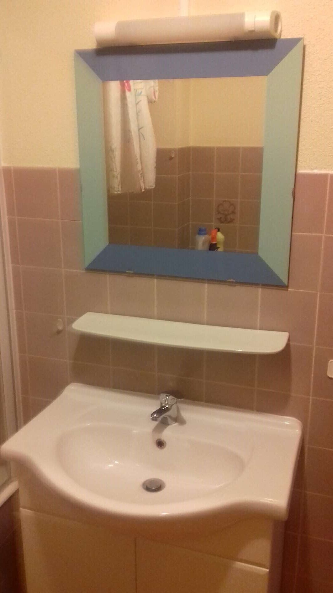 A bathroom with a white sink, a mirror above it, and a towel hanging on the wall.