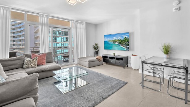 Una sala de estar moderna con un sofá, una mesa de centro de vidrio y un televisor.