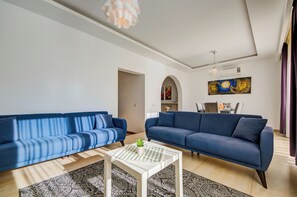 Un salon moderne avec deux canapés bleus, une table basse blanche et un tapis à motifs.