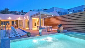 A modern outdoor pool area with lounge chairs, a hot tub, and a covered patio. - Extraordinary Villa With Private Pool & Steamsauna (Mellieha)
