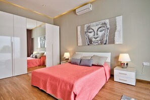 Quarto moderno com uma cama grande, mesas de cabeceira com luminárias, um guarda-roupa e um ar condicionado fixado na parede.