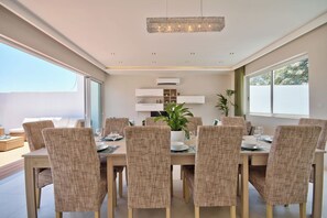 Uma área de refeições com cadeiras de vime, uma mesa de madeira e um lustre.