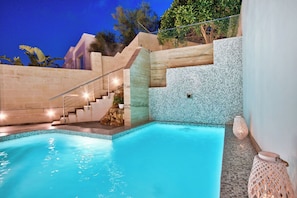 Una piscina con una pared de piedra y una escalera que sube a un nivel superior.