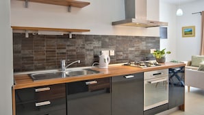 Una cocina moderna con encimera de madera, pileta de acero inoxidable y muebles de color negro.