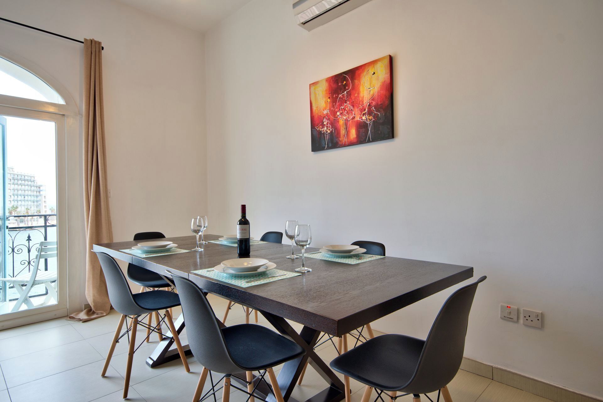 Un comedor con una mesa grande, seis sillas y una botella de vino.