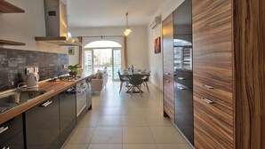 Una cocina moderna con una isla central, un comedor con mesa y sillas, y vistas a la ciudad a través de amplias ventanas.
