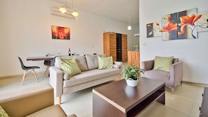 Una sala moderna con un sofá, sillones, una mesita de centro y un comedor con sillas y una mesa.