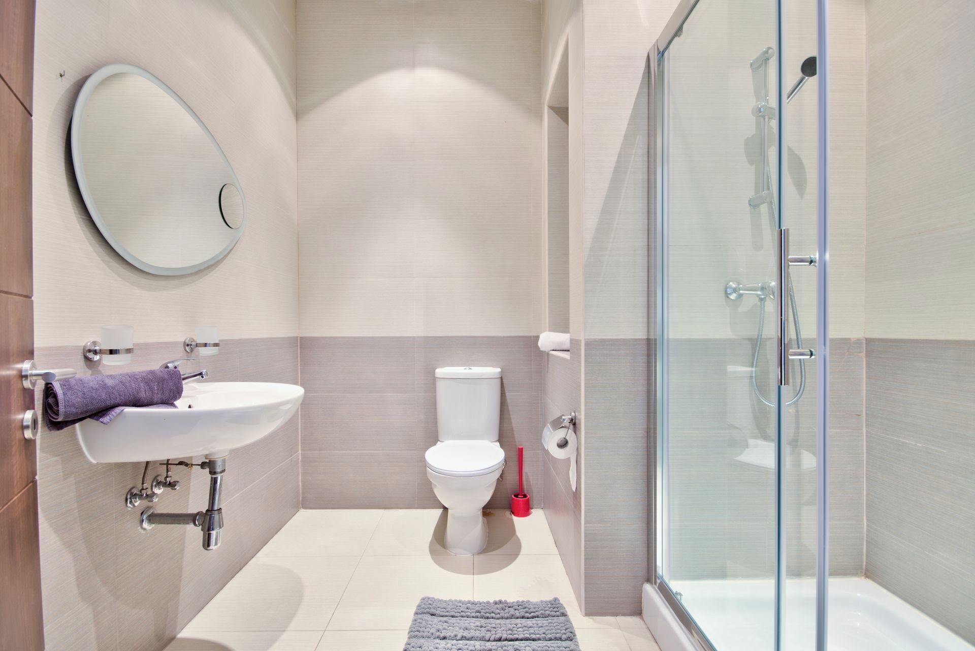 Un baño moderno con cabina de ducha de vidrio, un lavamanos blanco y un inodoro.