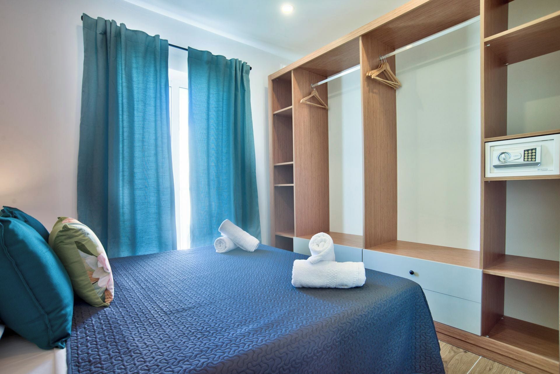 A bedroom with a bed, a wardrobe, and a window with curtains.