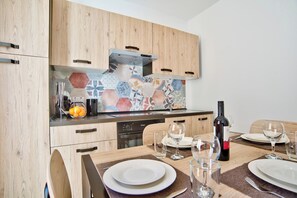 A modern kitchen with wooden cabinets, a colorful backsplash, and a dining area set for a meal.