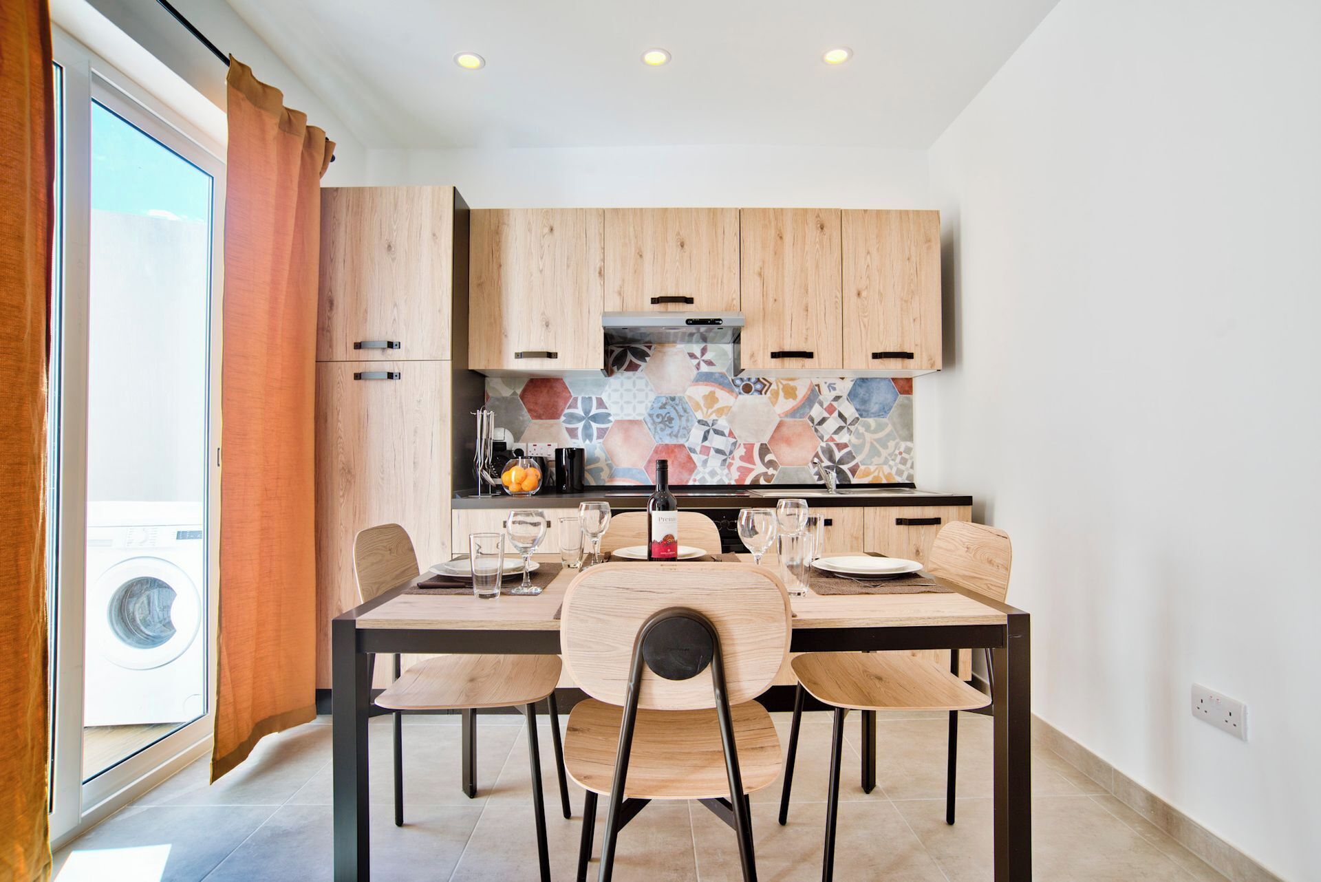 A modern kitchen with wooden cabinets, a tiled backsplash, and a dining area with a table and chairs.