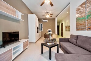 A modern living room with a flat-screen TV, a grey sofa, a coffee table, and a ceiling fan. - Central Flat With Traditional Maltese Balcony (Gzira)