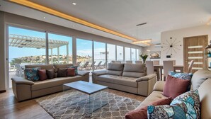 Un salon spacieux doté d’une grande fenêtre, d’un plafond pourvu d’un éclairage encastré et offrant une vue sur la mer.