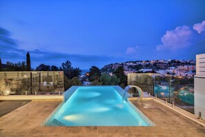 A rooftop pool with a clear view of a hillside town at dusk. - Prestigious Grand Villa With Luxurious Amenities (Mellieha)