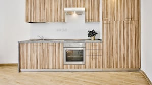 A modern kitchen with wooden cabinetry, a built-in oven, and a stainless steel sink. - Idyllic Penthouse Apartment With Sea View Balcony (Sliema)