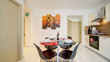 A modern dining area with a table set for four, a wine bottle, and abstract art on the wall.