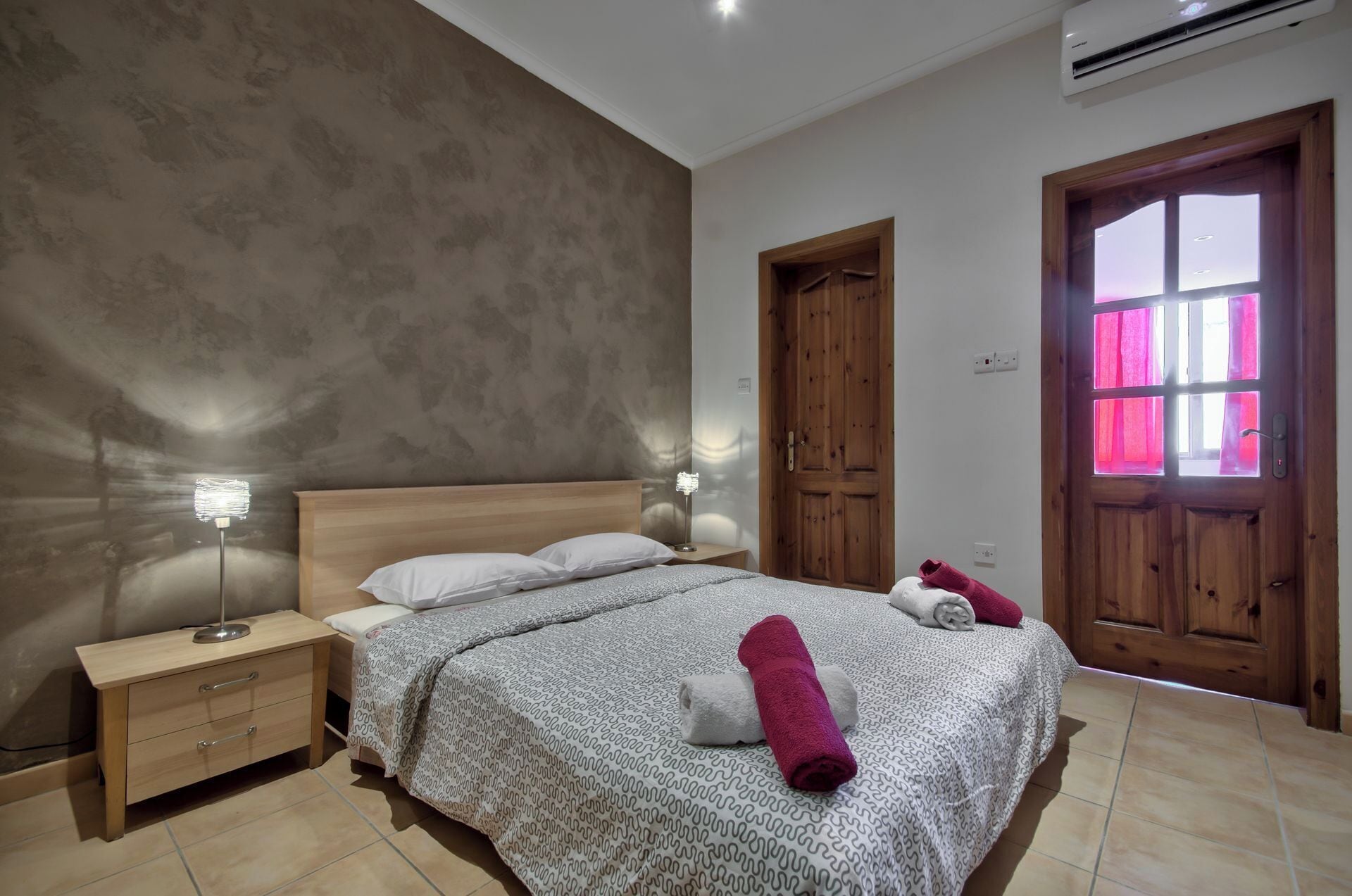 A bedroom with a bed, nightstand, and wooden doors.