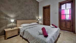 A bedroom with a bed, nightstand, and wooden doors. - Delightful Apartment With Traditional Balcony (Sliema)
