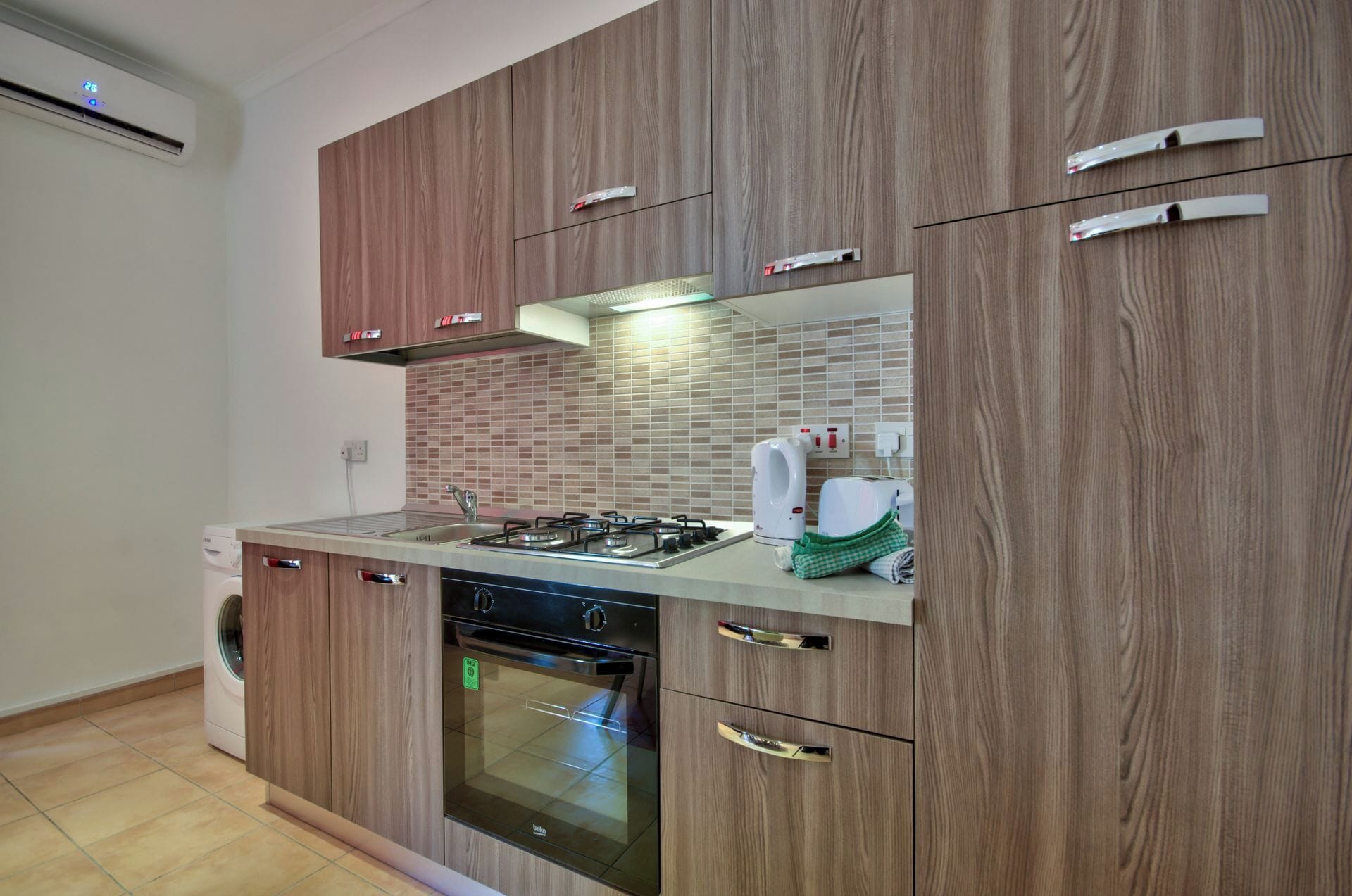 Una cocina moderna con armarios de madera, estufa a gas, lavavajillas y horno empotrado.